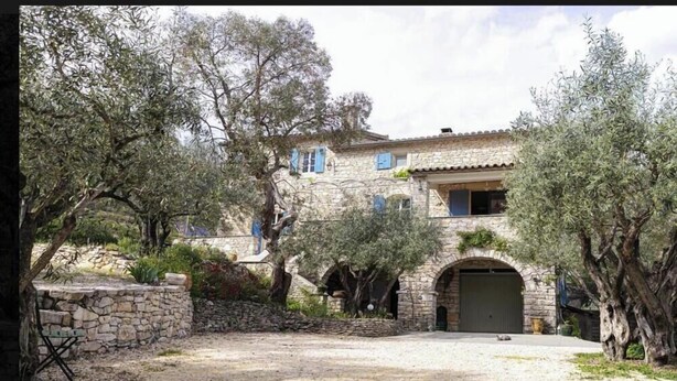 Un edificio de piedra con patio, arcos y olivos.