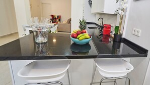 Un'isola nella cucina con una ciotola di frutta, un contenitore di vetro e due sgabelli da bar bianchi.