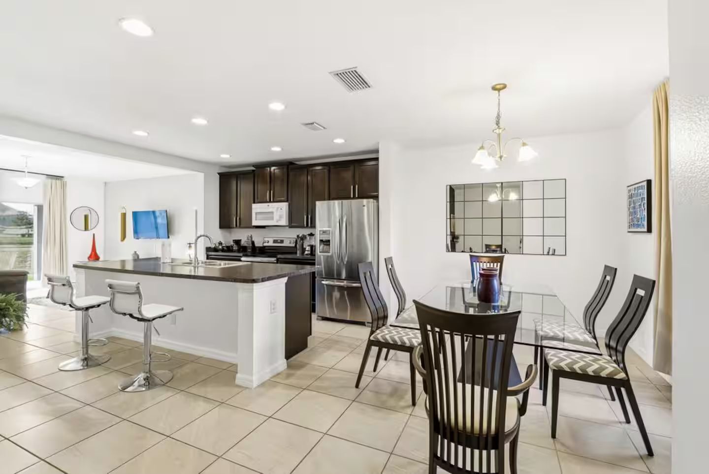 A modern kitchen with a central island, stainless steel appliances, and a dining area with a glass table and chairs.