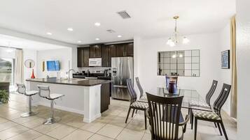 A modern kitchen with a central island, stainless steel appliances, and a dining area with a glass table and chairs.