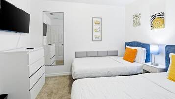 A hotel room with two beds, a TV, a dresser, and a mirror.