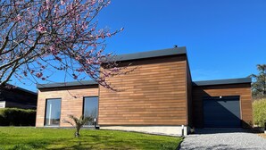 Een modern gebouw met twee verdiepingen, een houten gevel, grote garage deuren en een verzorgd gazon.