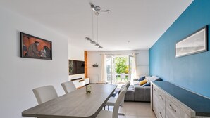 A modern kitchen with a dining area, a sofa, and a view of the outdoors. - Le Refuge Balnéaire - À 3km de la plage (Pornichet)