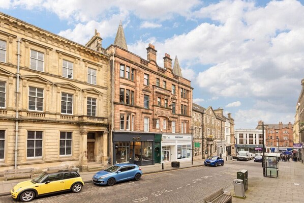 Calle con edificios históricos, una tienda de artesanía y coches aparcados.