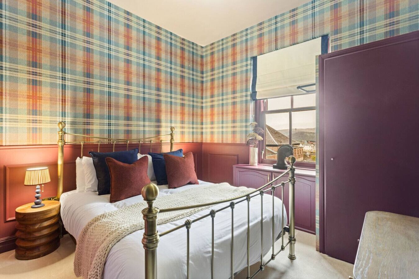 Quarto com cama, mesa de cabeceira, janela com vista e porta.
