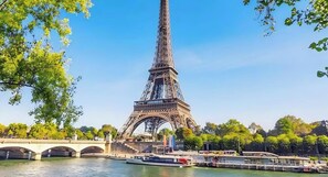 A Torre Eiffel com um rio e uma ponte ao primeiro plano.