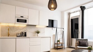 Eine moderne Küche mit weißen Schränken, einem eingebauten Ofen, einem schwarzen Fernseher und Holzdielen.