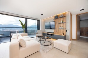 A modern living room with a sofa, coffee table, TV, and a city view. - Stunning City View 3 bedroom flat • Custom Design • Remote Ready (Medellín)