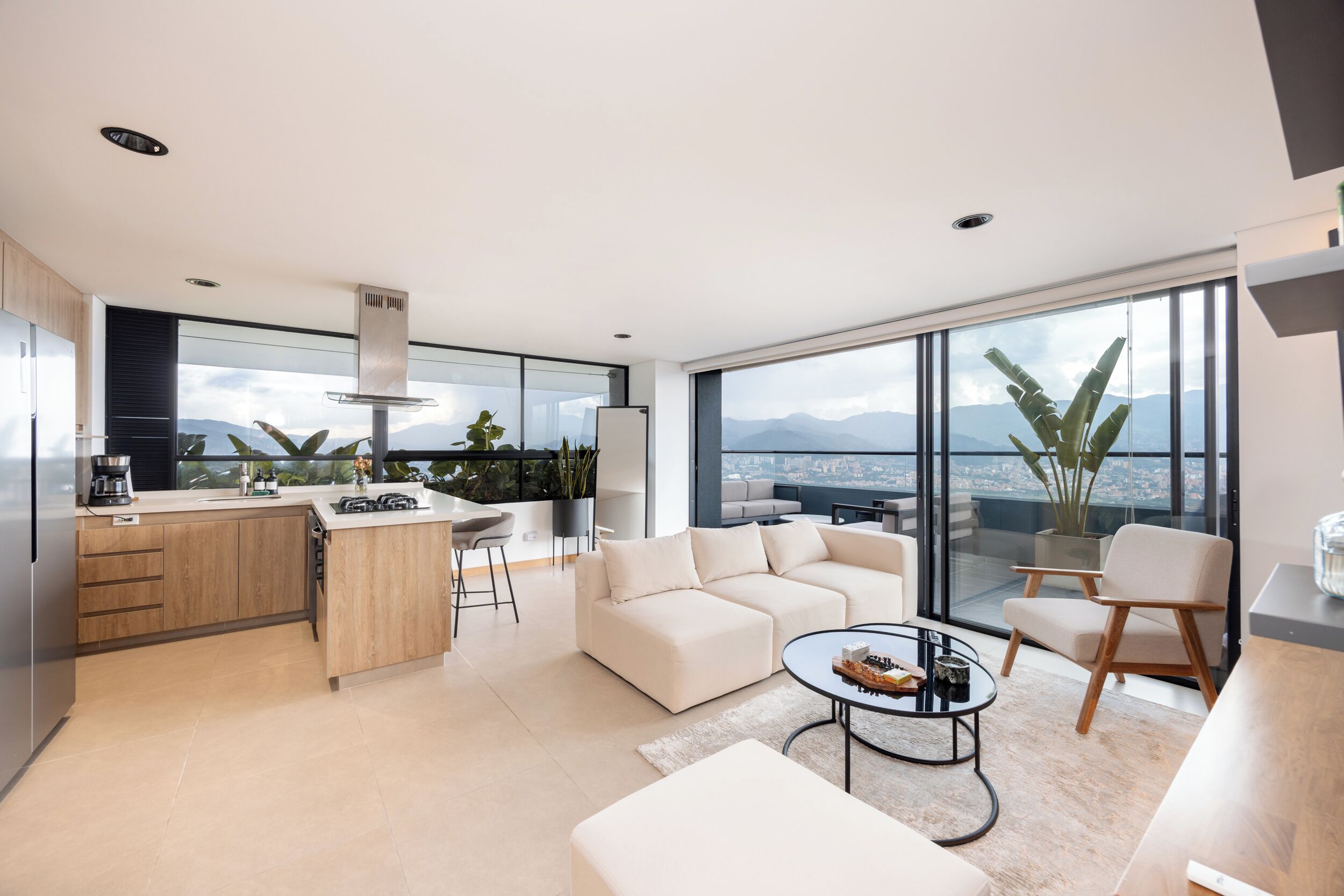 A modern living space with a kitchen, dining area, and seating area with a view of mountains.