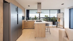 Een moderne keuken met een groot kookeiland, roestvrijstalen apparatuur en uitzicht op de omgeving.