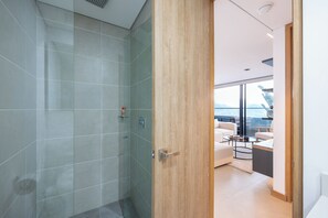 Uma casa de banho moderna com cabine de duche em vidro e porta de madeira para zona de estar com varanda.