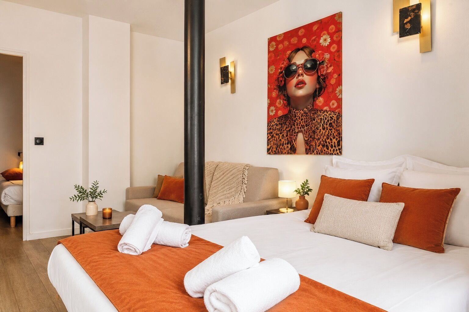 Une chambre d’hôtel avec un lit, un canapé, une table de chevet, une lampe et un tableau au mur.
