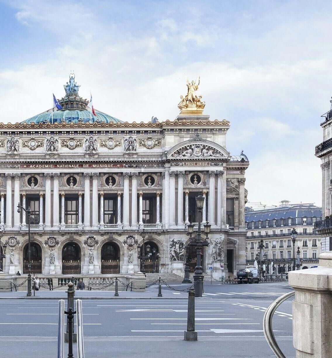 Un bâtiment historique à l’architecture classique, caractérisé par une statue imposante sur la façade et un dôme.