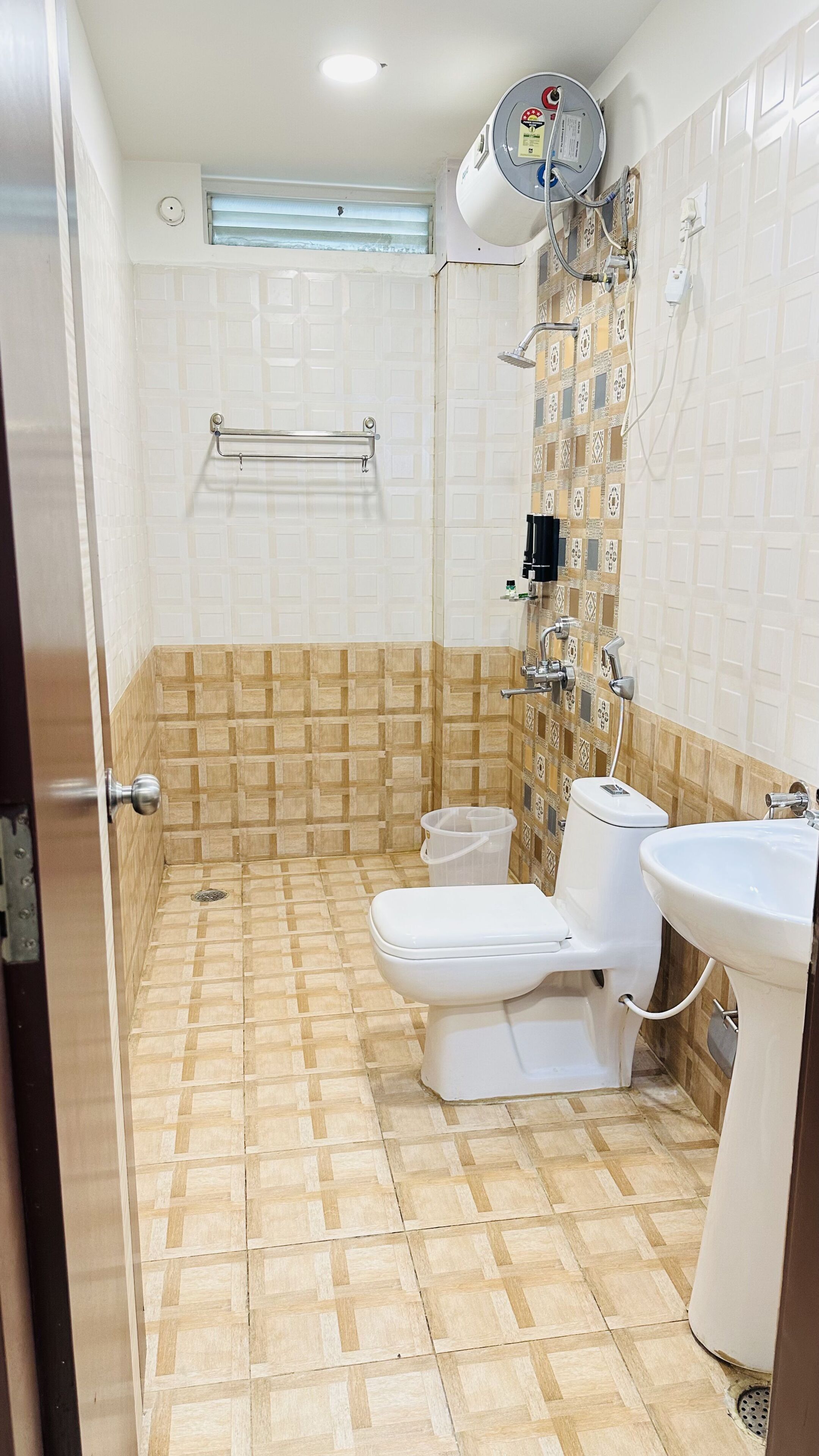 A bathroom with a toilet, bidet, and sink, tiled walls, and a shower head.