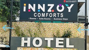 Une enseigne d’hôtel avec les inscriptions « INNZOY COMFORTS » et « HOTEL », des flèches pointant vers la gauche et la droite, et un panneau indiquant « INTERDIT DE STATIONNER ».