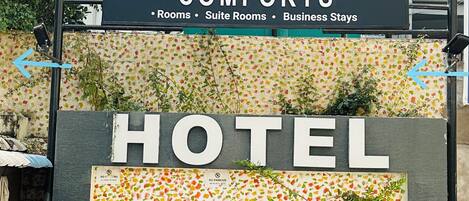 A hotel sign with 'INNZOY COMFORTS' and 'HOTEL' text, arrows pointing left and right, and a 'NO PARKING' sign.