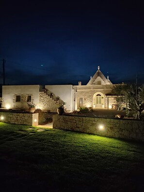 A building with a stone facade, a central arched entrance, and a triangular roof. - Complex of trulli and lamie in Itria Valley - charm and relaxation by the pool (Puglia)