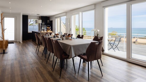 Ein stilvoller Essbereich mit Meerblick, Holzboden und einem großen Fenster.