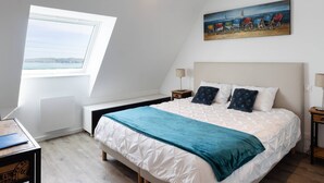 Ein Schlafzimmer mit einem Bett, einem Gemälde, einem Fenster und einem Schreibtisch.