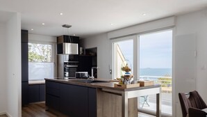 Eine moderne Küche mit einer zentralen Kochinsel, integrierten Geräten und Blick aufs Meer.