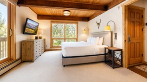 Ein Schlafzimmer mit Bett, Kommode, Fernseher, Fenster und Tür.