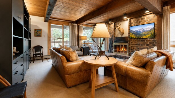 Ein gemütliches Wohnzimmer mit Ledersofas, einem Kamin und einem Fernseher.