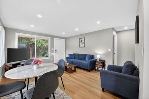 A modern living room with a white marble table, blue sofa, and a flat-screen TV.