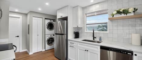 Una cocina moderna con electrodomésticos de acero inoxidable, armarios blancos y lavadora secadora integrada.