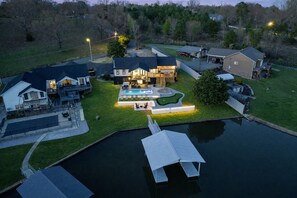 A residential property with a swimming pool, a dock, and a well-maintained lawn.