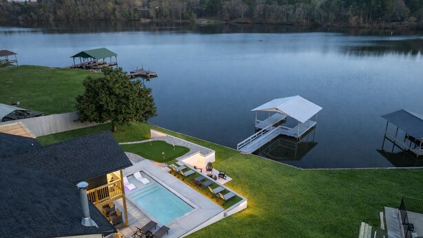 A lakeside property with a swimming pool, outdoor seating, and a dock. - Lakefront Sleeps 18 w/ Pool, Dock, Putting Green, Hot Tub! Hot Springs (Hot Springs)