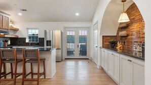 A modern kitchen with a central island, white cabinetry, and a view through glass doors. - Lakefront Sleeps 18 w/ Pool, Dock, Putting Green, Hot Tub! Hot Springs (Hot Springs)