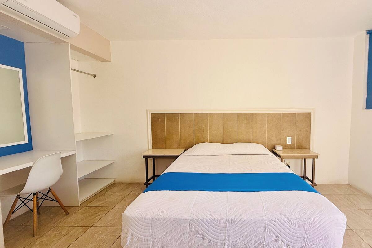 Un dormitorio con cama, escritorio, silla y televisor.