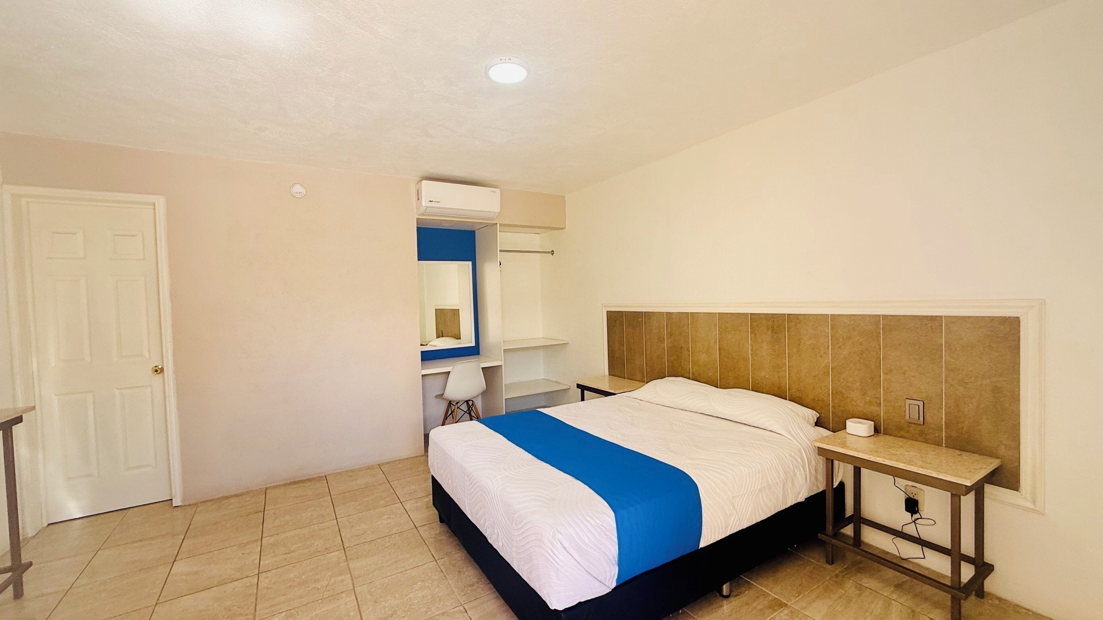 A bedroom with a bed, a bedside table, a wardrobe, and a mirror.