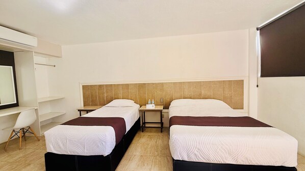 Une chambre d’hôtel avec deux lits, un bureau, une chaise et un téléviseur.