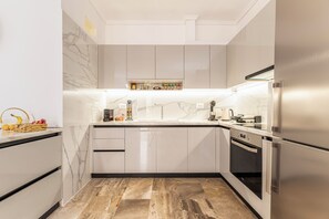 A modern kitchen with marble countertops, stainless steel appliances, and a built-in oven.