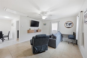 A living room with a sofa, a recliner, a TV, a desk, and a chair.