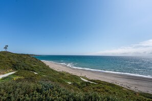 A coastal landscape with a beach, a clear sky, and a distant view of the ocean. - Alcaidesa Golf and Beach Resort: Relaxation with Pool, Mountain Views and Prime Location (La Alcaidesa)