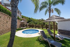 Un pati interior amb piscina, gandules, zona de barbacoa i un para-sol de palla.