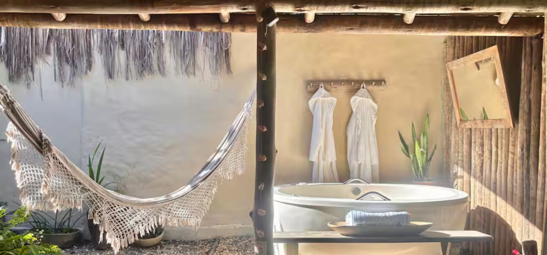 A hammock, a bathtub, and a sink in a rustic bathroom setting.