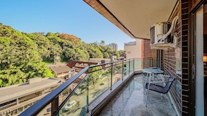 Ein Balkon mit Glasgeländer, einem Tisch und zwei Stühlen.