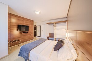 Quarto moderno com cama, paredes de painel de madeira, televisão e estantes embutidas.