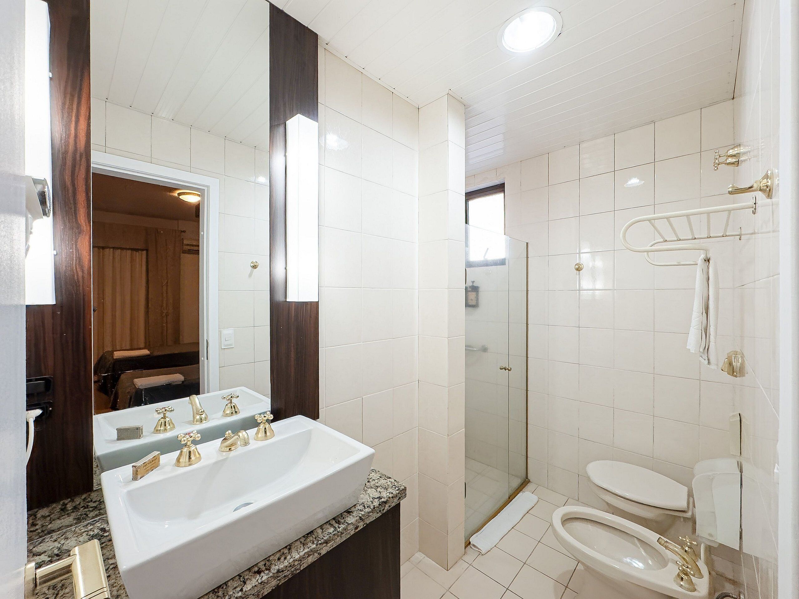 A bathroom with a double sink, a glass shower enclosure, and a toilet.