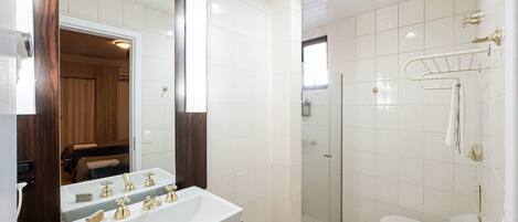 A bathroom with a double sink, a glass shower enclosure, and a toilet.