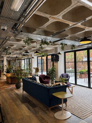 Un interior moderno con sofá modular, mesa redonda y plantas en macetas.
