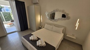 Quarto de hotel com cama, guarda-roupa, espelho e vista para o exterior.