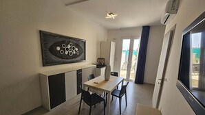 Sala de estar moderna com área de jantar, uma grande pintura abstrata e uma porta de vidro deslizante que dá para uma varanda.