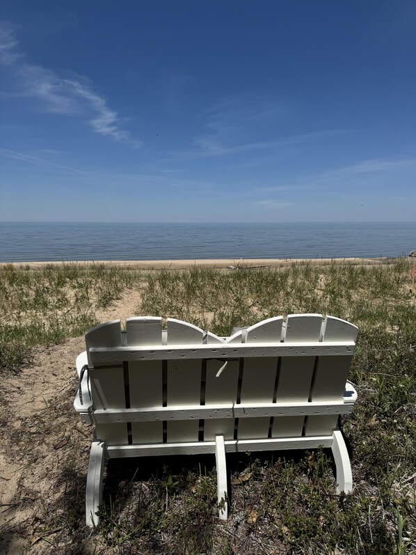Un banc blanc sur une plage de sable, offrant une vue dégagée sur l’océan.