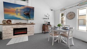 Ett modernt vardagsrum med en öppen spis, ett matbord och en stor TV som är monterad på väggen.