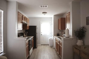 A kitchen with wooden cabinets, a refrigerator, and a white countertop.