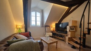 Ein gemütliches Loft-Wohnzimmer mit einer Ledersofa, einem Holztisch, einem Flachbildfernseher und einem Weinkühlschrank.